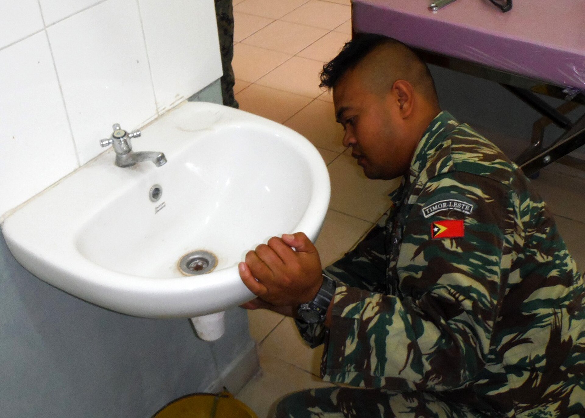 Tradesperson repairing plumbing beneath a sink